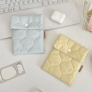 Close-up of quilted cotton storage pouches with soft diamond patterns and button closure