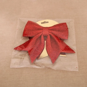 Detail of a bright red glitter Christmas bow ornament with golden backing on fabric