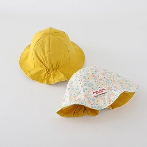 Détail des chapeaux de soleil réversibles pour bébés en jaune et imprimé floral en coton