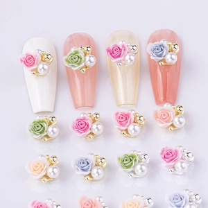 Macro detail of 3D resin rose nail art charms with pearls on colorful manicure tips
