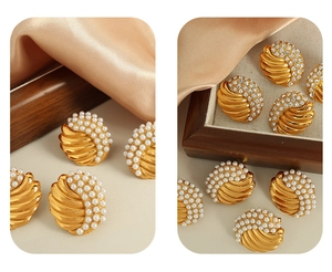 Macro detail of vintage gold shell earrings with white faux pearls and sparkling rhinestones