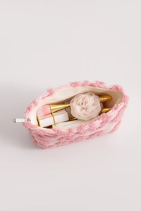 Détail intérieur de la trousse à maquillage en peluche rose avec pinceaux et cosmétiques