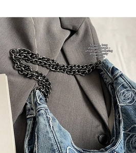 Detailed macro of denim tote bag featuring rose embroidery and rustic frayed edges