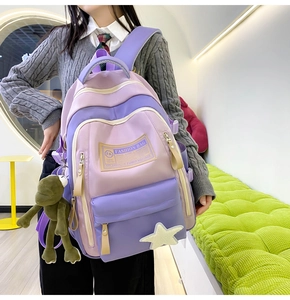 Detail of purple student backpack with green frog pendant and fashion branding