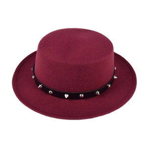 Detail of burgundy flat top wool hat with black leather strap and silver metal punk spikes
