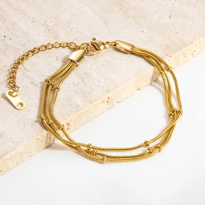 Detail of 18K gold triple-layer snake chain bracelet with round beads and lobster clasp