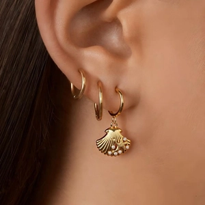 Gold stainless steel shell and star pendant hoop earrings set worn by a female model