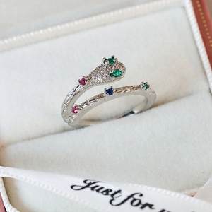 Macro shot of silver snake ring with green stone eyes and colorful gemstone body detail