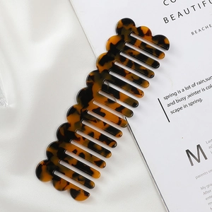 Wavy tortoise shell acetate comb with wide teeth on white silk and magazine background
