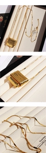 Macro shot of gold square woven pendant showing reflective finish and intricate texture