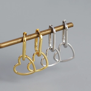 Detail of geometric heart earrings in gold and silver finish with hollow heart charms