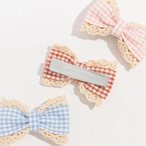 Close-up of three plaid bow hair clips with lace trim and metal clip back detail