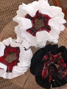 Detailed view of three oversized plaid scrunchies with lace trim on a circular wooden board