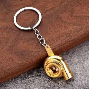 Golden turbocharger car keychain with metal ring and chain on rustic wood background