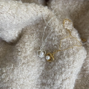 Detail of silver and gold heart pendant necklaces with pearls on soft fabric