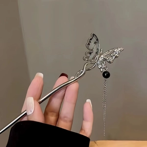 Detailed close-up of a silver butterfly hair pin with delicate metal tassel and beads