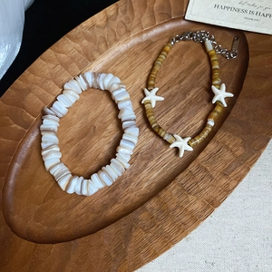 Detail of beaded shell bracelets with starfish charms on a rustic wooden tray