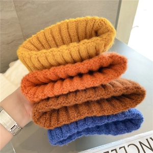 Detailed knit texture of thick cable-knit beanies in yellow, orange, brown and blue