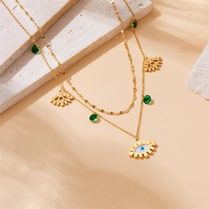 Layered gold stainless steel necklace featuring green droplets and blue evil eye charms