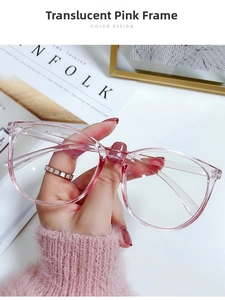 Détail de la monture de lunettes oversize rose transparent tenue devant un magazine Kinfolk