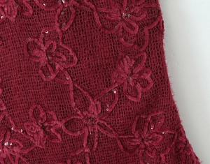 Macro shot of dark red mesh fabric with 3D floral embroidery and sequins on the dress