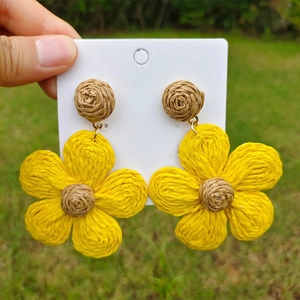 Detail showing handcrafted yellow raffia flower earrings with bohemian woven texture