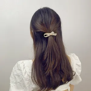 Detail showing elegant gold ribbon hair clip with pearls on a model back hair