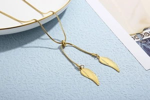 Detail of elegant gold snake chain necklace featuring twin feather wing pendants