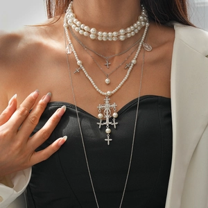 Detail of layered faux pearl necklaces with a large rhinestone encrusted cross pendant