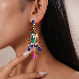 Close-up of vintage palace style gold drop earrings with multi-colored gemstones on model