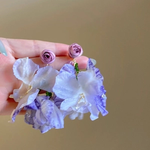 Macro detail of purple floral earrings with chiffon petals and golden metal stems