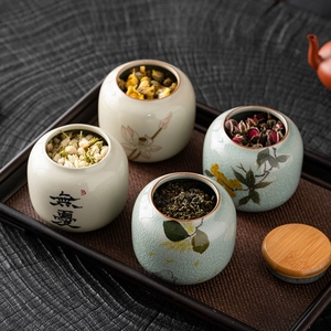 Miniature ceramic tea canisters with lotus patterns and wooden lids on a dark tray