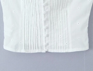 Dettaglio top in cotone bianco con ricamo inglese, pieghe e bottoni in tessuto