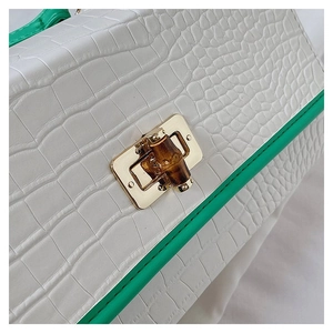 Close-up of white crocodile texture bag with golden bamboo lock and green edges