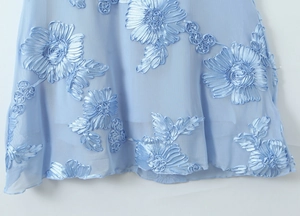 Détail d'une robe bleu clair montrant le tissu en maille et la broderie ruban 3D florale