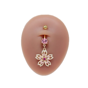 Close-up of golden cherry blossom belly ring with pink zircon stones on skin model
