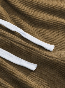 Close-up of brown corduroy fabric texture and two-tone woven drawstring on pants