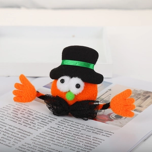 Cute orange plush felt character wearing a black top hat and green ribbon on a book