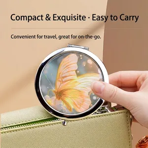 Portable silver metal folding makeup mirror with yellow butterfly design in a handbag