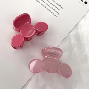 Detail of small pink hair claws in opaque and translucent finish on a soft fabric