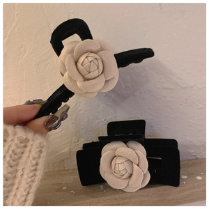 Close-up of elegant black velvet hair claw and clip with white 3D camellia flower detail