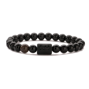 Detail view of black beaded bracelet featuring an engraved Capricorn zodiac symbol charm
