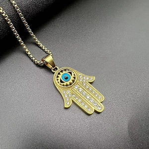 Détail de la main de fatma dorée avec œil bleu et strass brillants sur chaîne box
