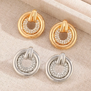 Close-up of gold and silver hollow circular earrings with pavé set cubic zirconia