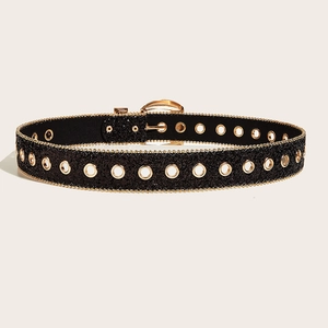 Detail of black glitter belt with gold eyelets and buckle on minimalist background
