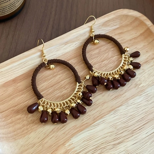 Detailed macro view of Bohemian earrings with brown cotton rope and red teardrop beads