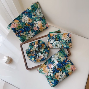 Macro view of floral cotton storage pouch set including cosmetic bags and hair scrunchie