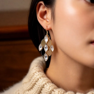 Detailed close-up of vintage gold teardrop earrings with glass leaves on a female model