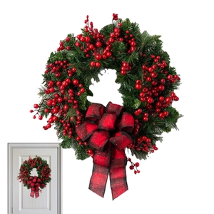 Close-up of artificial pine needles with red berries and a red black buffalo plaid bow