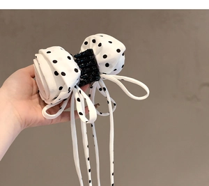 Detailed view of the white polka dot fabric bow hair claw clip with long ribbon streamers